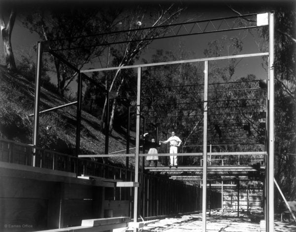Charles and Ray Eames stand in the frame of the Eames House as it is being built