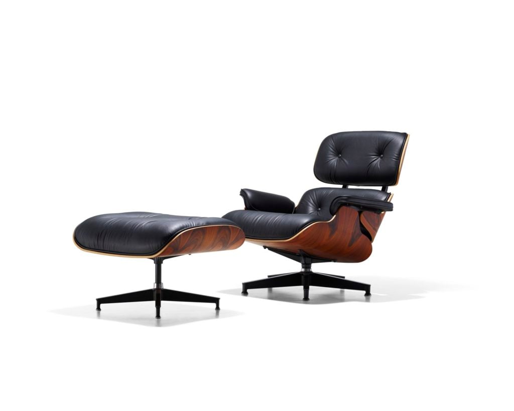 a photo of the Eames Lounge Chair and Ottoman.It is a molded dark-brown plywood chair with black leather and a black 5 pointed aluminum base.