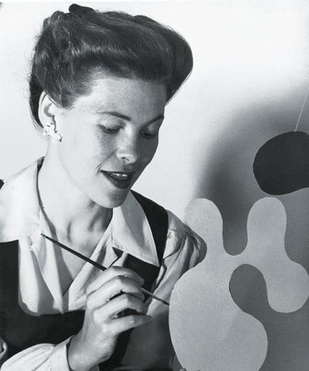 A profile view of Ray Eames painting an Eames Plywood Mobile