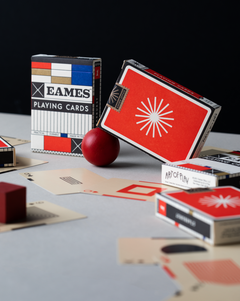 Decks of Eames Playing Cards with single cards splayed on the table around them